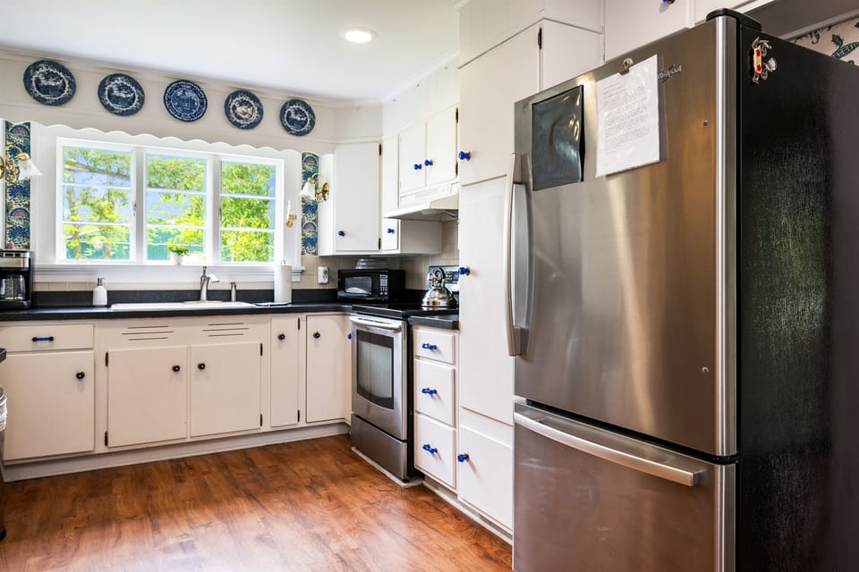 Charming vintage kitchen with modern stainless steel appliances, classic blue accents, and a scenic view above the sink 🌿🍽️💙
