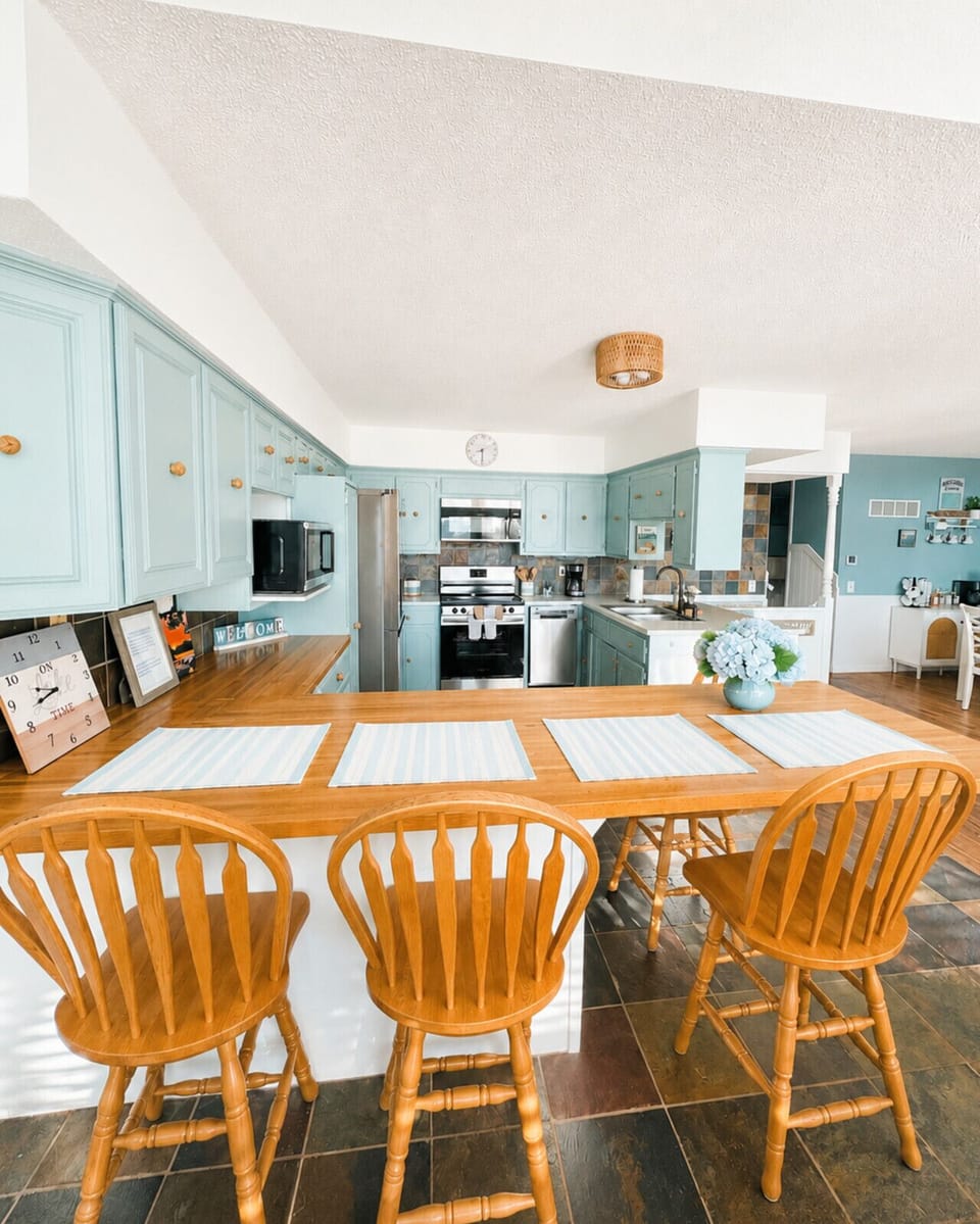 Bright open kitchen with breakfast bar seating and coastal-inspired design—perfect for entertaining, family meals, and relaxing lake house stays.
