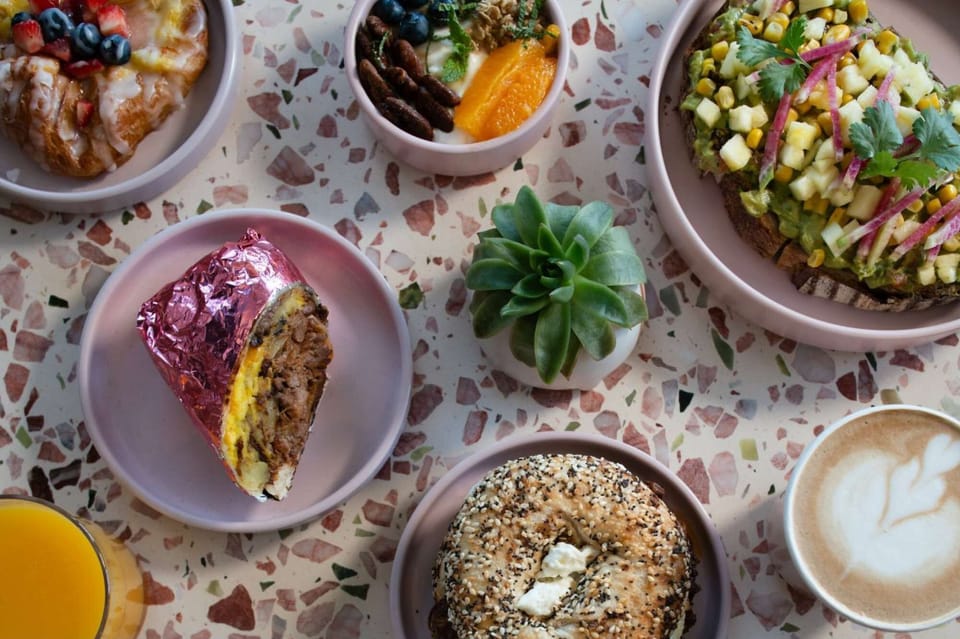 Bagel, burrito, toast, fruit, and coffee on a table