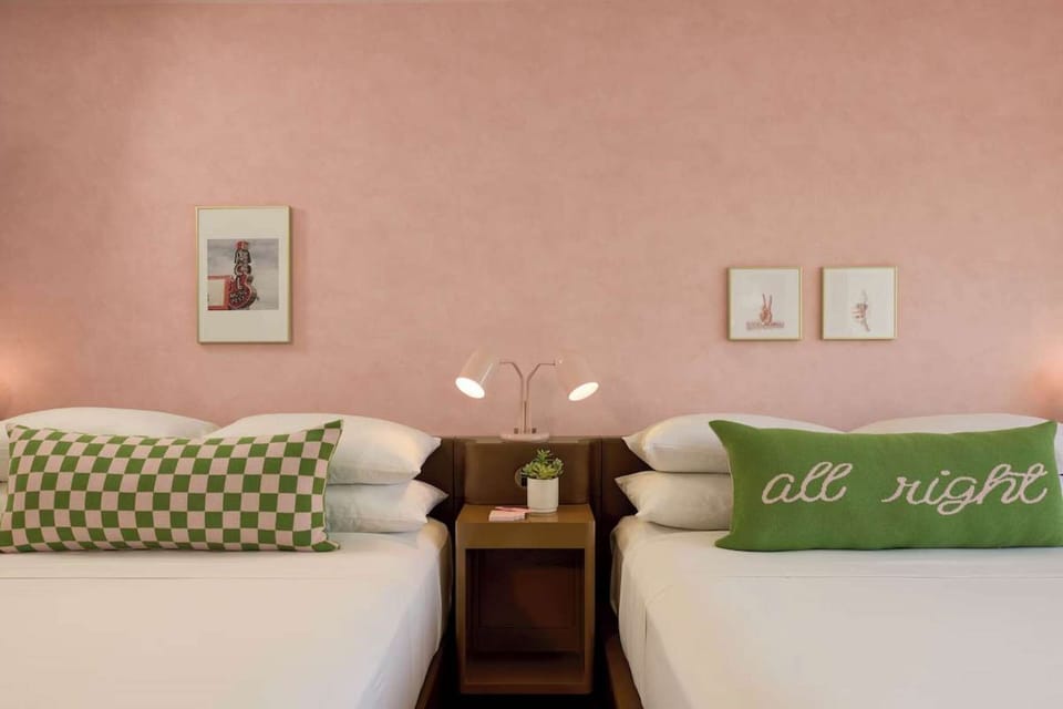 Two beds with green accent pillows and soft lighting
