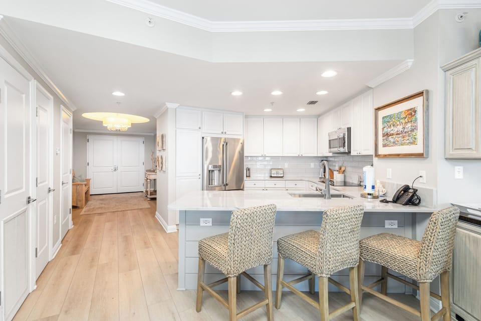 Gather around the spacious island with coastal-style seating, where morning coffee and meal prep feel effortless. Stainless appliances, ample counter space, and soft natural light create your perfect home-away-from-home kitchen.