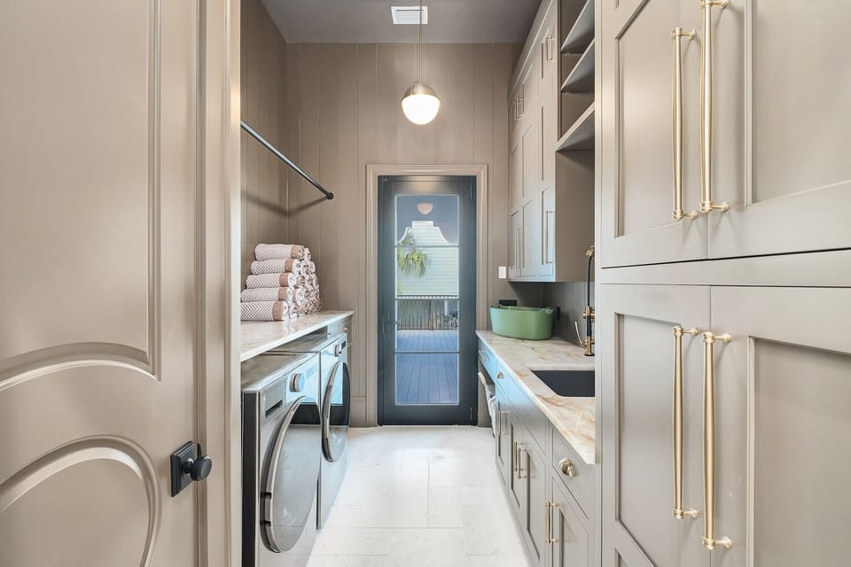 Your private laundry room features elegant grey cabinetry, marble countertops, and modern appliances to keep your wardrobe fresh throughout your stay.