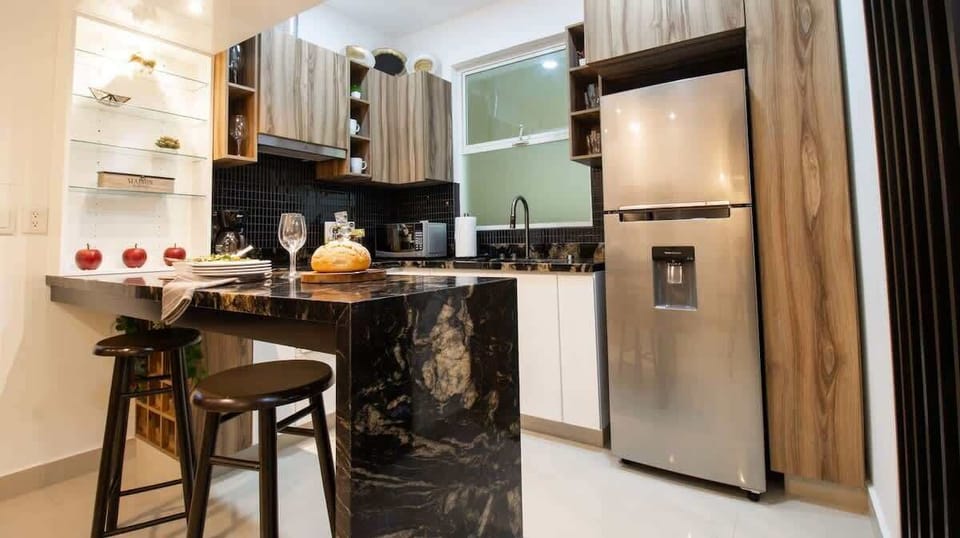 A kitchen with a granite breakfast bar and two stools