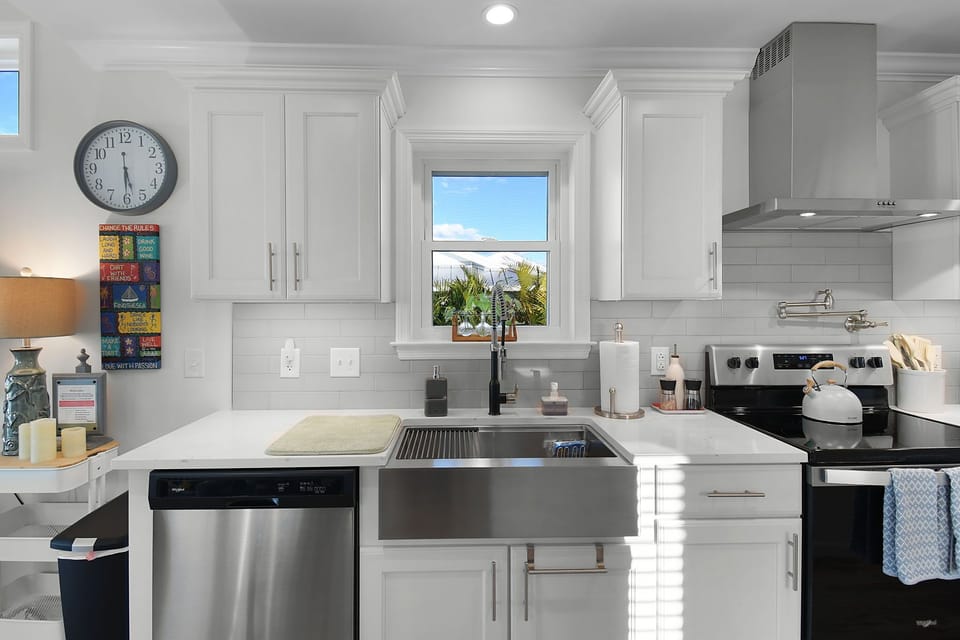 Bright main kitchen area with stainless steel appliances and coastal design
