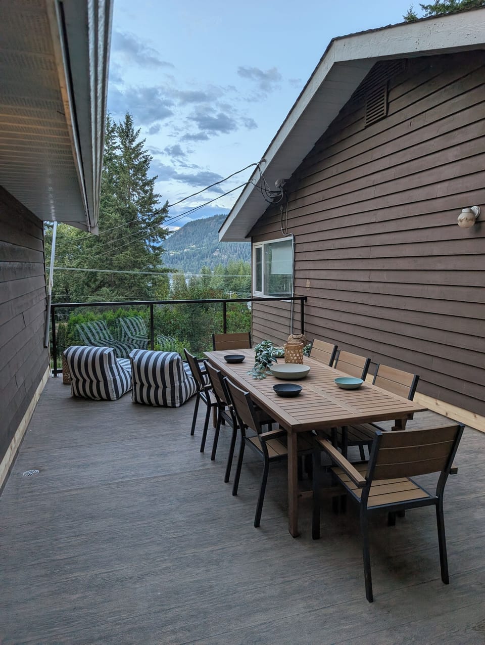 Deck between main house and bunkhouse with outdoor dining space and loungers