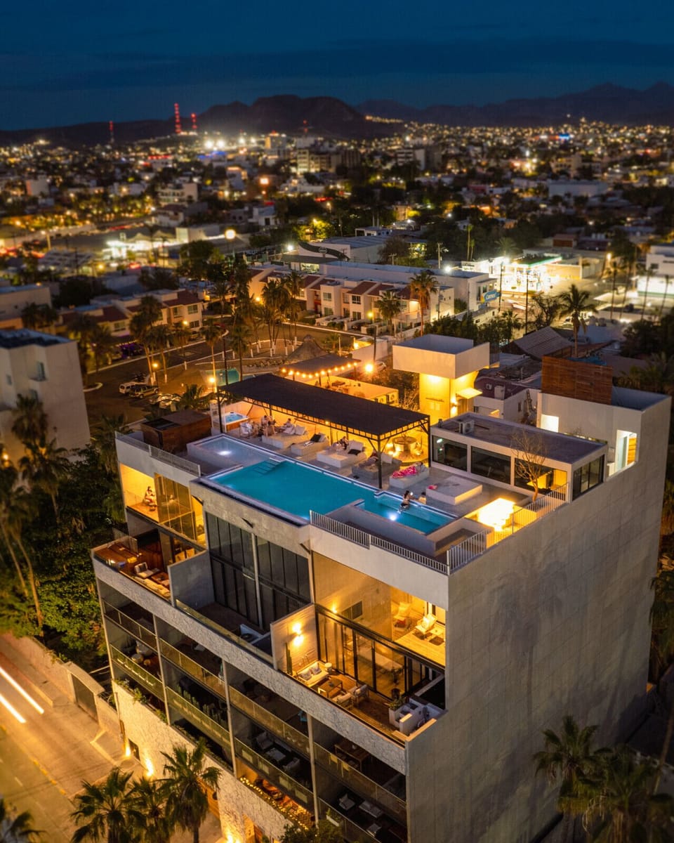 The building shines with elegance, crowned by a stunning rooftop that comes to life at night — glowing with soft ambient lighting and offering breathtaking views of the city and sea. A perfect invitation to unwind under the stars.