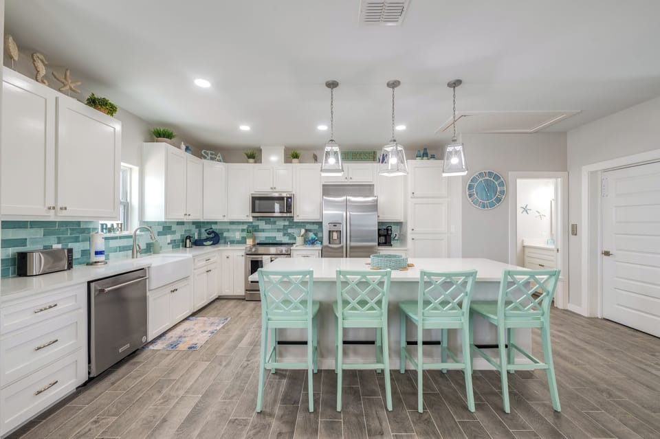 Your spacious kitchen features coastal charm with sea-glass accents, modern stainless appliances, and a breakfast bar perfect for morning coffee.