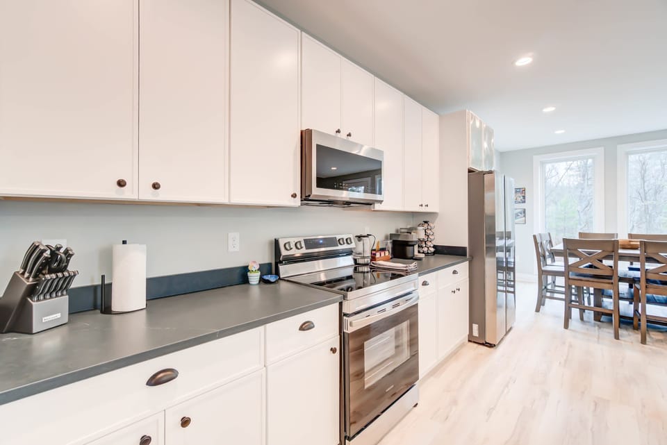 Natural light fills the fully equipped kitchen and the dining set on the right, creating a warm and inviting atmosphere.