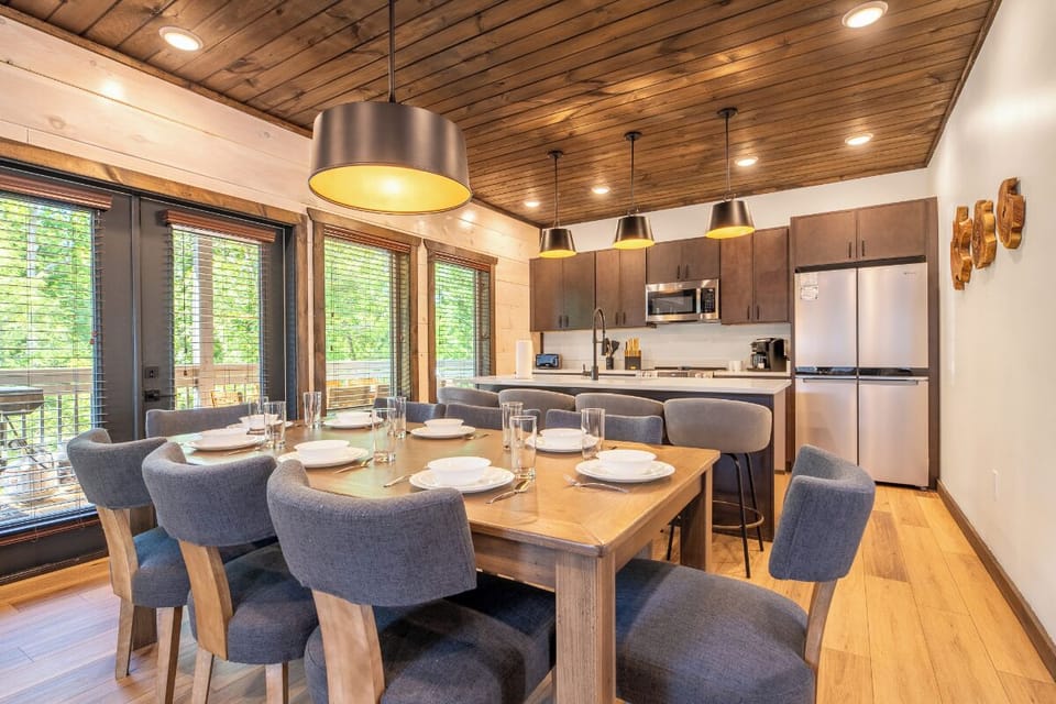 Gather around the warm wood dining table with modern pendant lighting, flowing seamlessly into your fully-equipped kitchen—ideal for memorable meals together after a day of adventure.