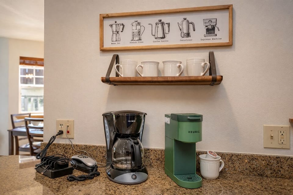 Start your mornings right with your personal coffee station featuring both drip and Keurig options, complete with mugs and charming coffee-themed art.