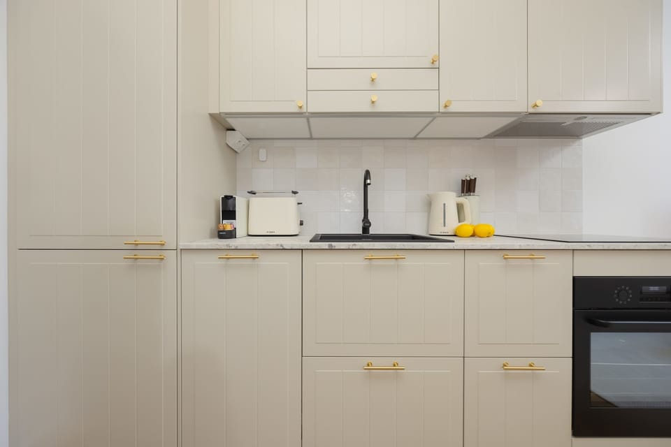A galley kitchen layout featuring sleek white cabinets, a black oven, and under-shelf lighting for a clean look.