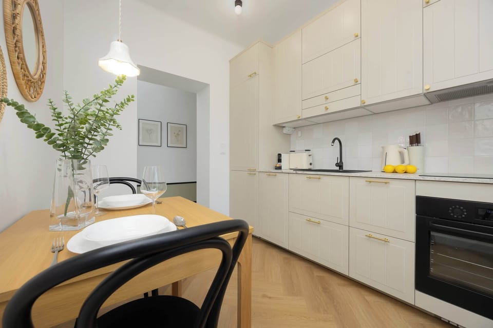 A minimalist white kitchen with black countertops, open shelving, and a few decorative items on the surface.