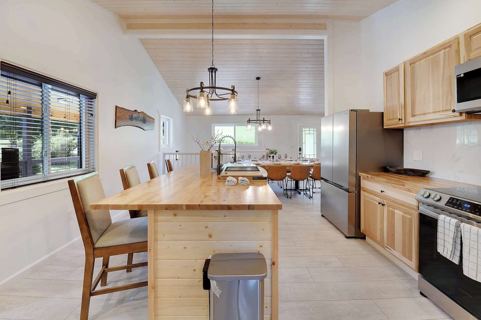 Open kitchen with a wooden island and modern stainless steel appliances.