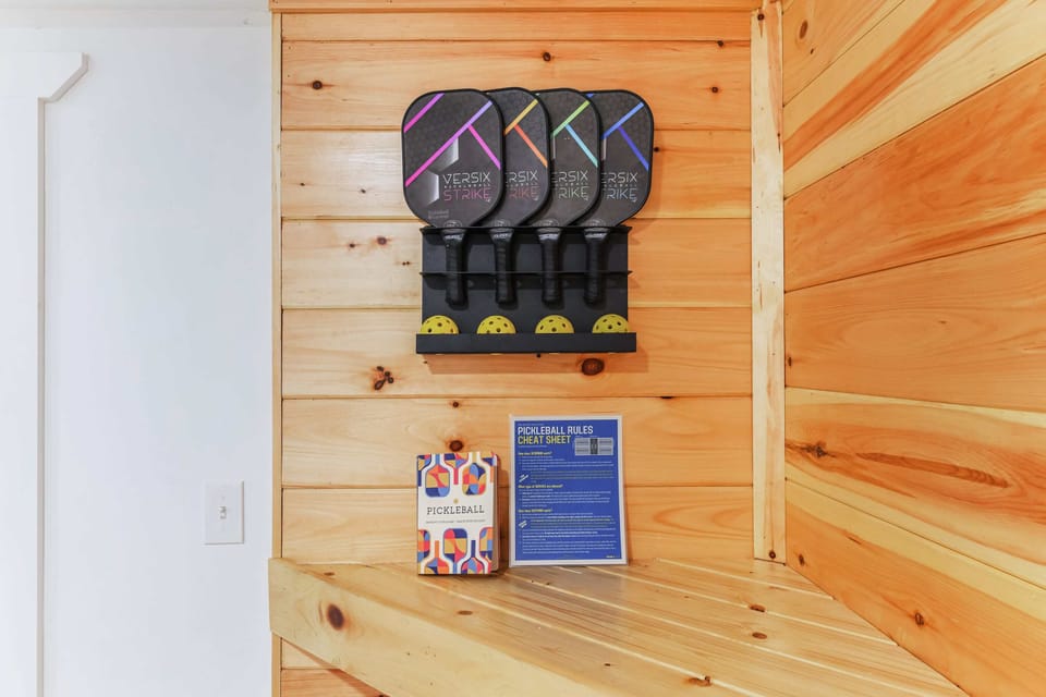 Pickleball paddles and balls neatly organized on a wooden wall rack in a cozy cabin setting.