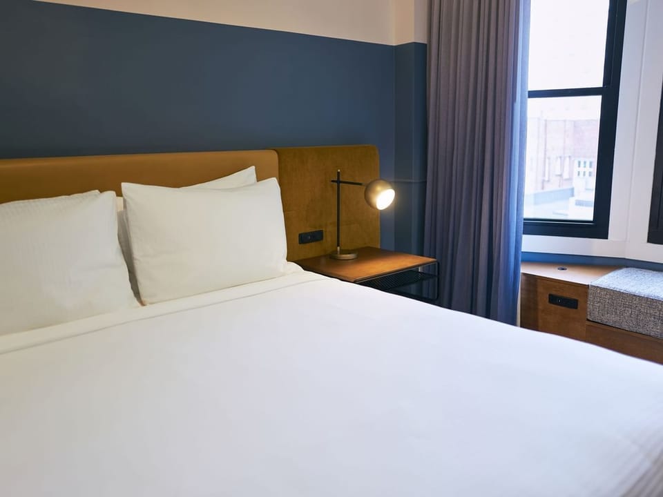 Unwind in crisp linens beside a bright city window nook
