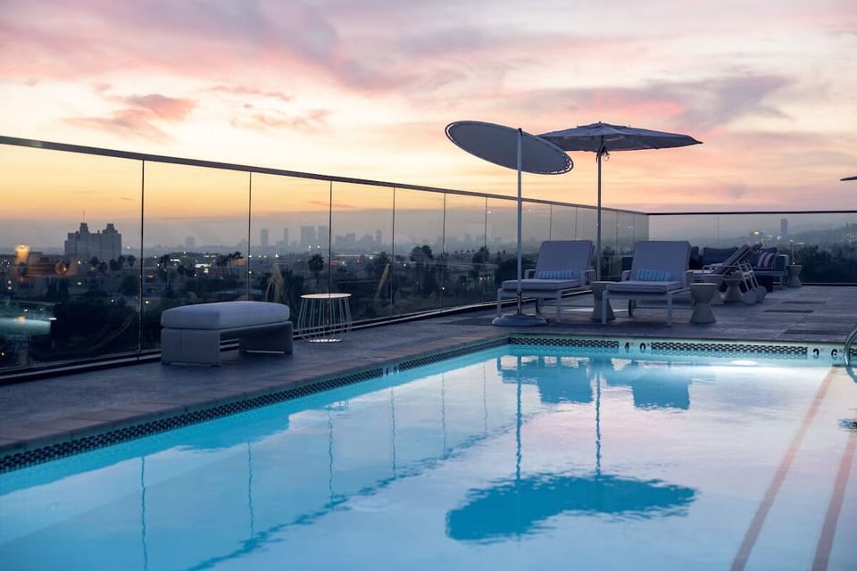 Soak in sunset serenity beside the rooftop pool and skyline.