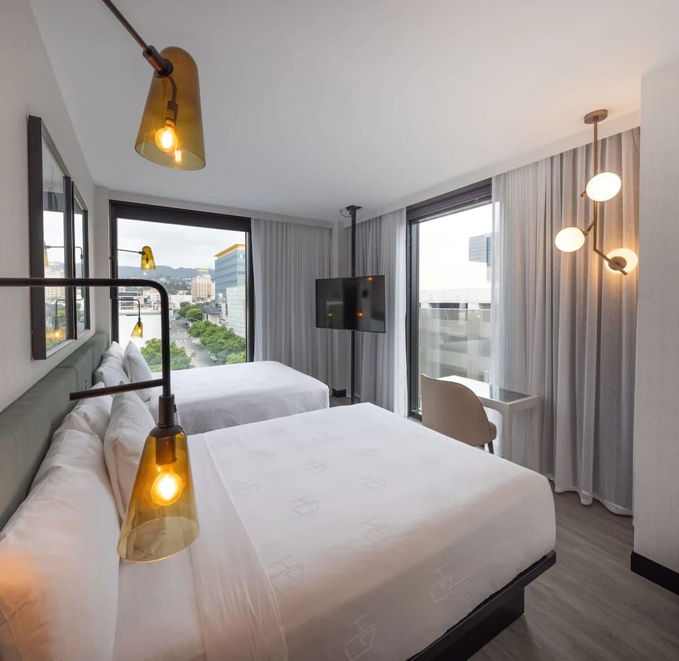 Recharge in a serene two-bed setup with warm designer lighting.