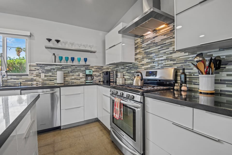 Sleek kitchen with gas range, mosaic backsplash, and premium appliances