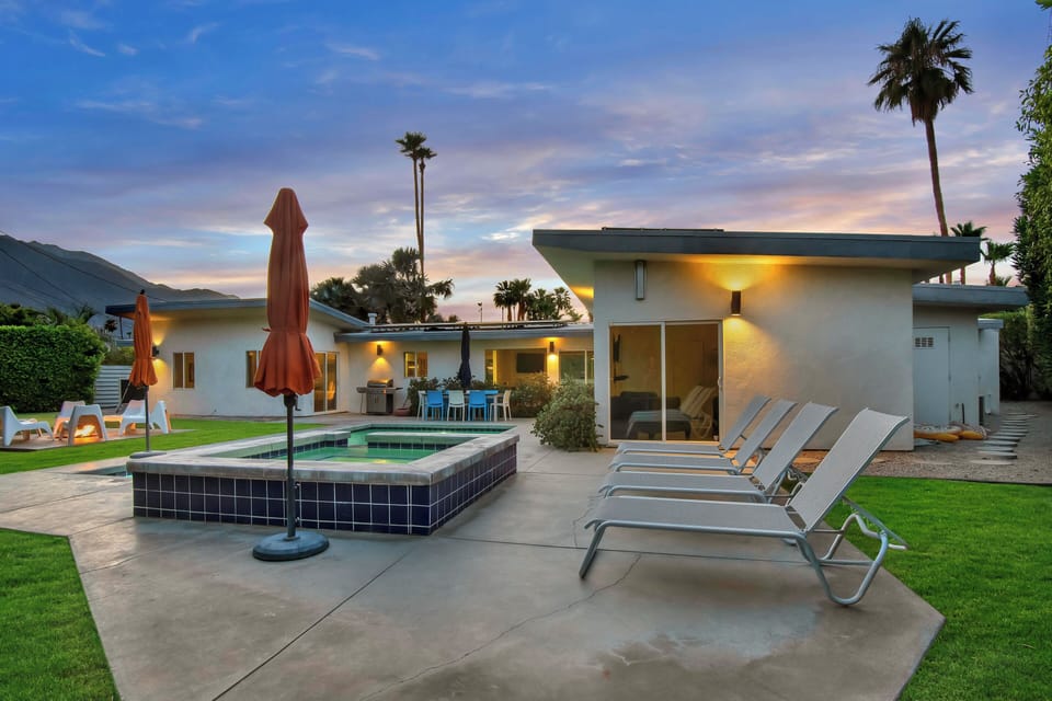 Twilight pool and spa with lounge chairs and warm architectural lighting