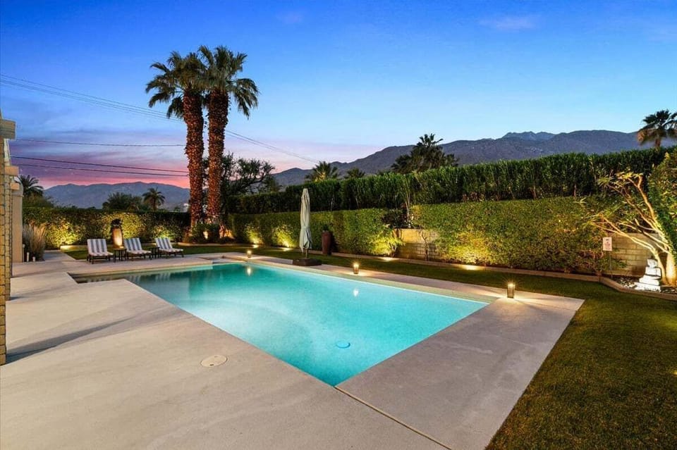 Resort-style pool glowing beneath a colorful desert sunset