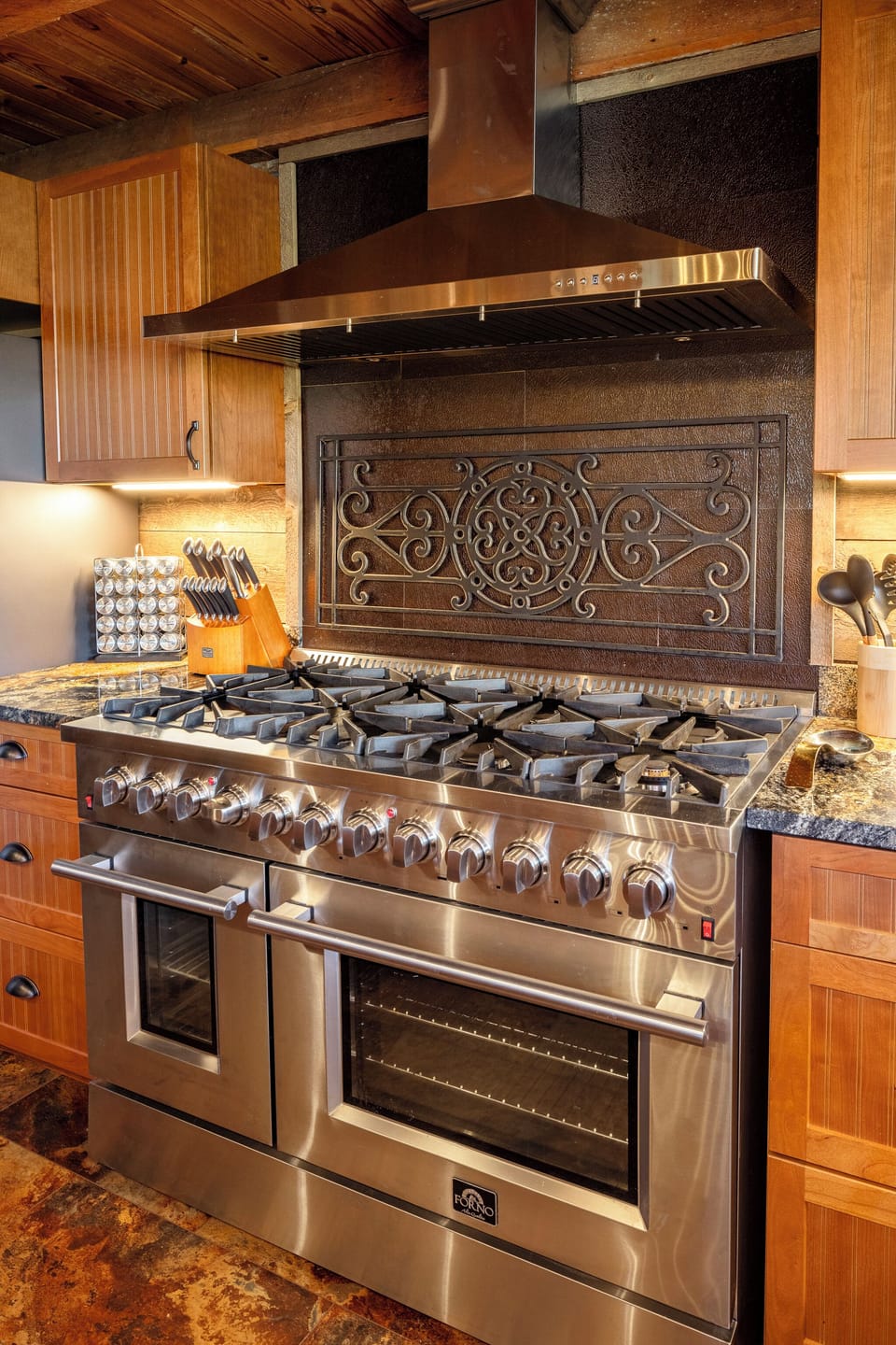 Cook like a chef in this luxury kitchen featuring a professional-grade Forno gas range, double ovens, and a stunning custom backsplash. Perfect for family meals or gourmet creations during your peaceful mountain getaway!