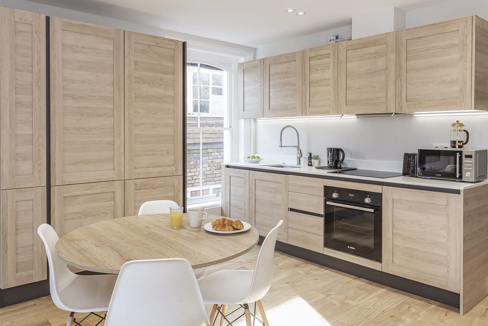 This bright, fully-equipped kitchen features sleek light-wood cabinetry, all the modern appliances you need, and a dedicated dining space.