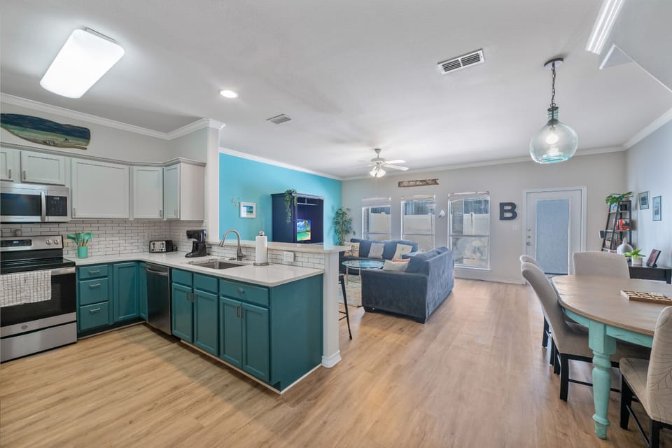 Your spacious open-concept retreat flows seamlessly from the stylish turquoise kitchen to comfortable living space, perfect for gathering and creating memories together.