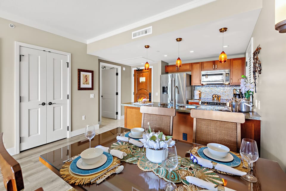 Your elegant dining space flows seamlessly into a modern kitchen, perfectly set for memorable meals with warm pendant lighting and tropical-inspired décor.