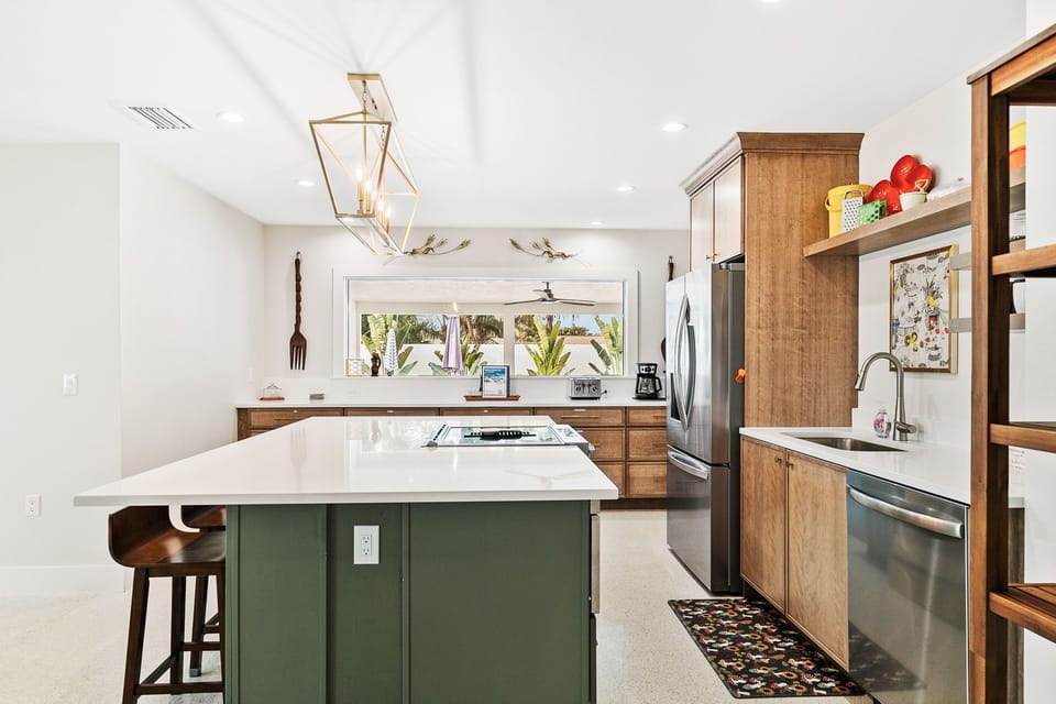 Step into your gourmet kitchen where warm wood cabinetry meets sleek marble countertops, creating the perfect space for morning coffee or evening meals with views of lush greenery outside