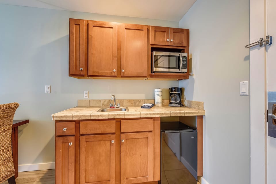 Kitchen including a small microwave, fridge and coffee maker.