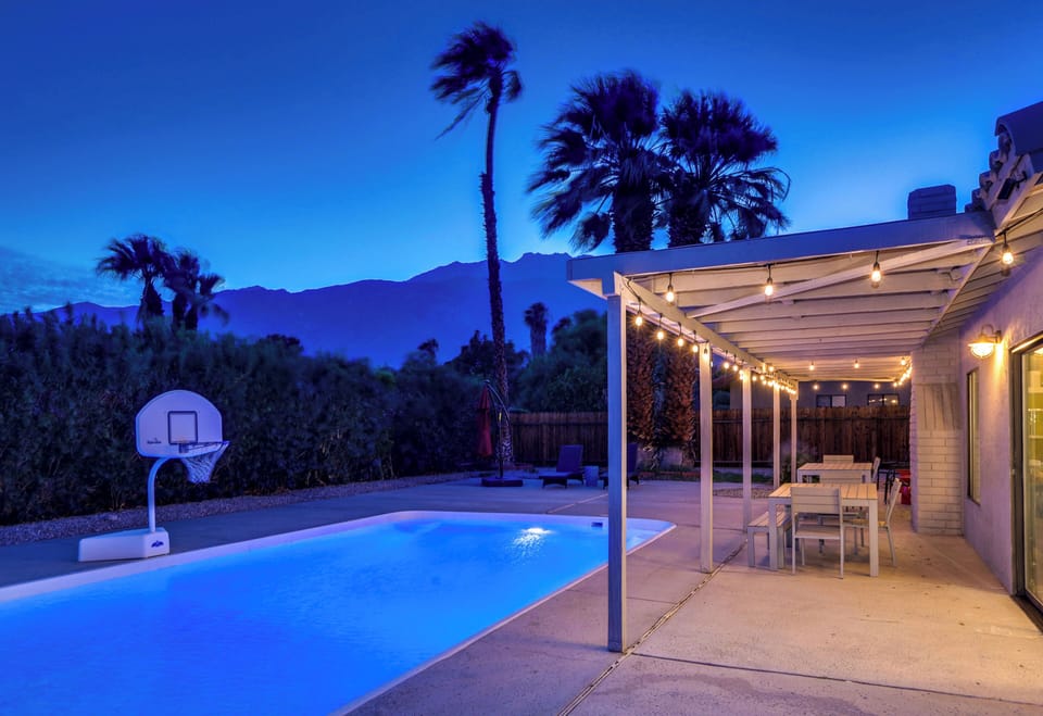Evening pool and patio with string lights, mountain views, and outdoor dining
