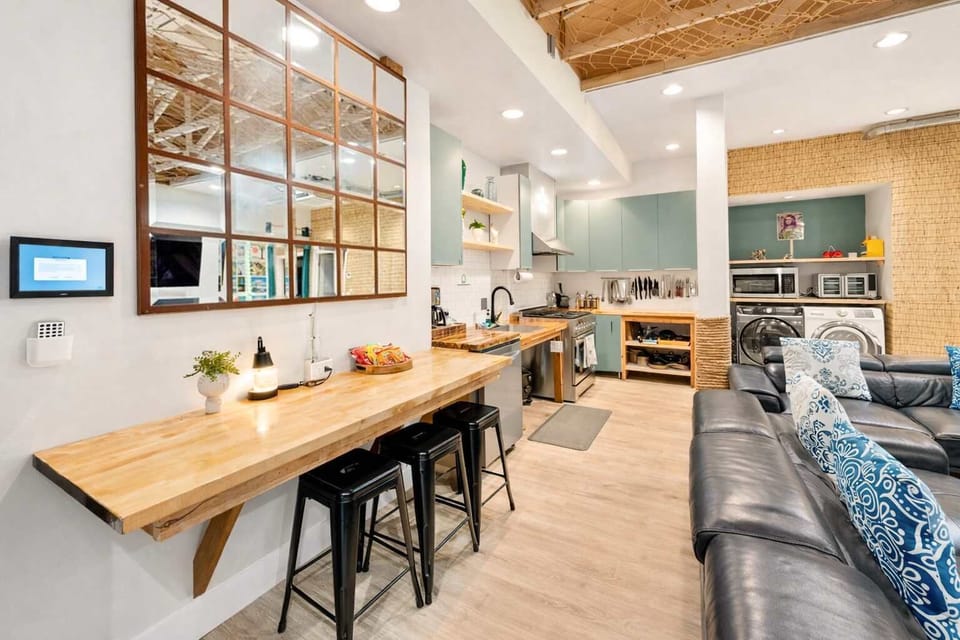 Open-Concept Kitchen and Living Space with Wood Counter Seating, Modern Appliances, and Relaxed Resort Design — A Social, Welcoming Area Perfect for Cooking, Dining, and Gathering

