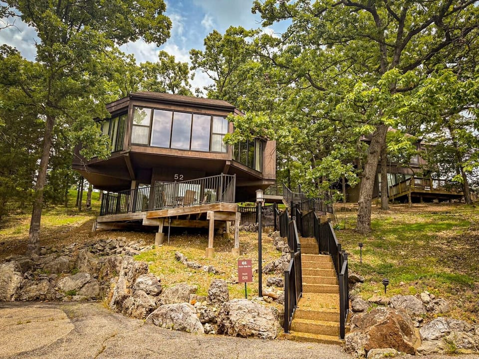 This modern elevated home offers a unique `treetop` living experience, blending seamlessly with the surrounding lush natural landscape. Multiple large windows allow for abundant natural light and scenic views, making this a bright and inviting retreat.