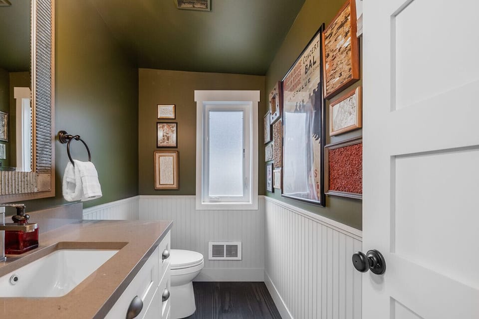 The Half Bathroom – A stylish half bath with bold green accents and modern fixtures.