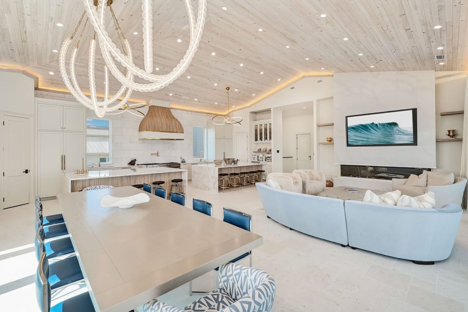 Picture yourself in this stunning open-concept retreat, where coastal elegance meets modern comfort. Relax on plush seating, gather around the spacious dining table, or whip up meals in your chef's kitchen—all under a show-stopping chandelier and whitewash