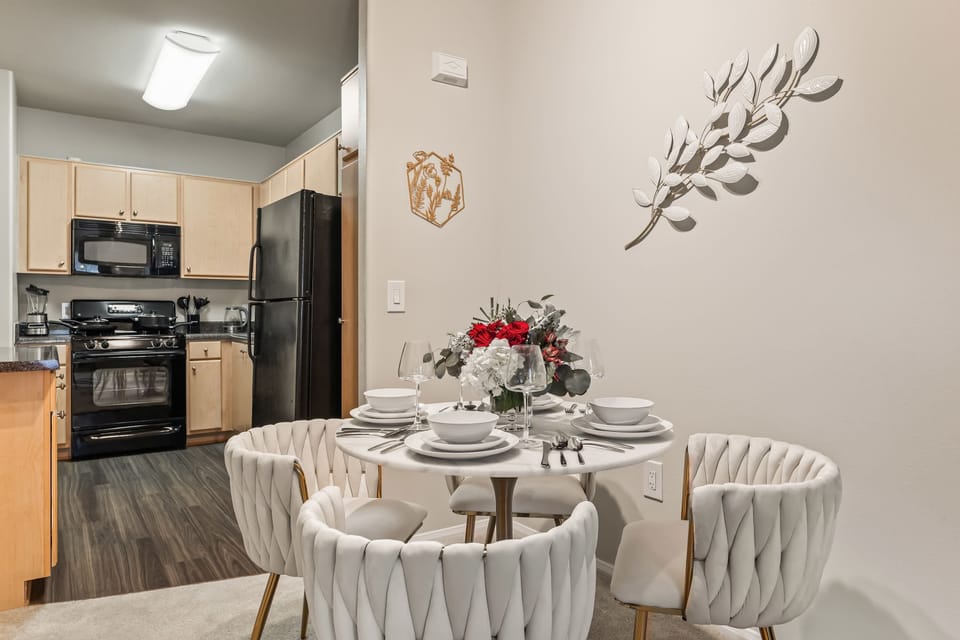 Open kitchen and dining area view featuring a round table and plush chairs under warm lighting.