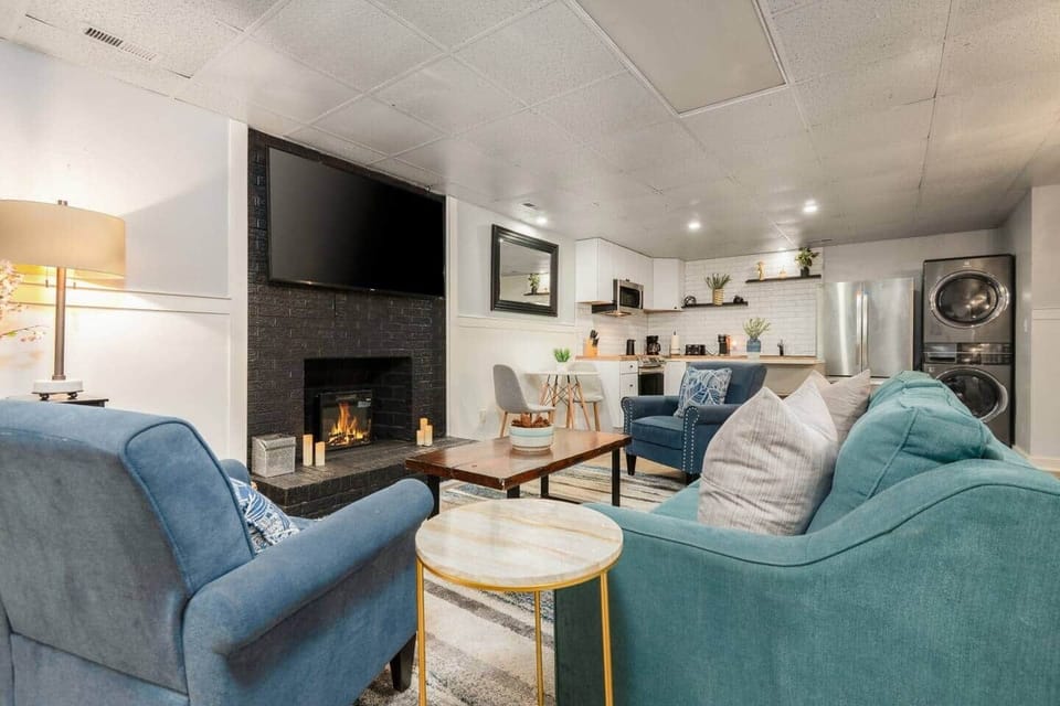 Cozy basement living room with a full kitchen, bathroom, bedroom, Smart TV, and air hockey table. Perfect for relaxing or playing—plus easy access to the second and third floors via the interior stairwell.