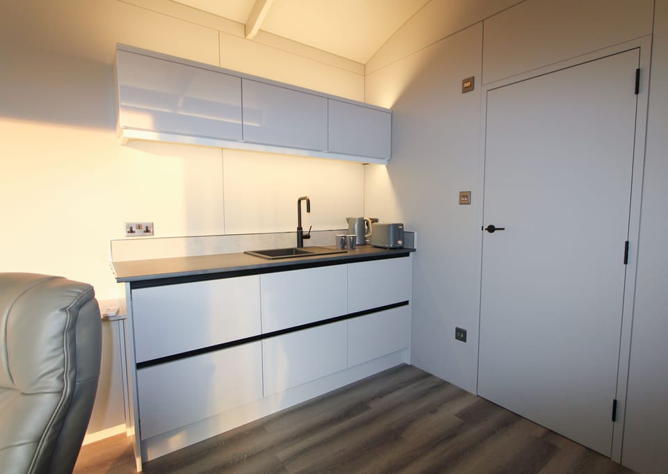 Mini kitchen with a breakfast bar, microwave, twin hob, kettle, air fryer and fridge and the door to the shower room