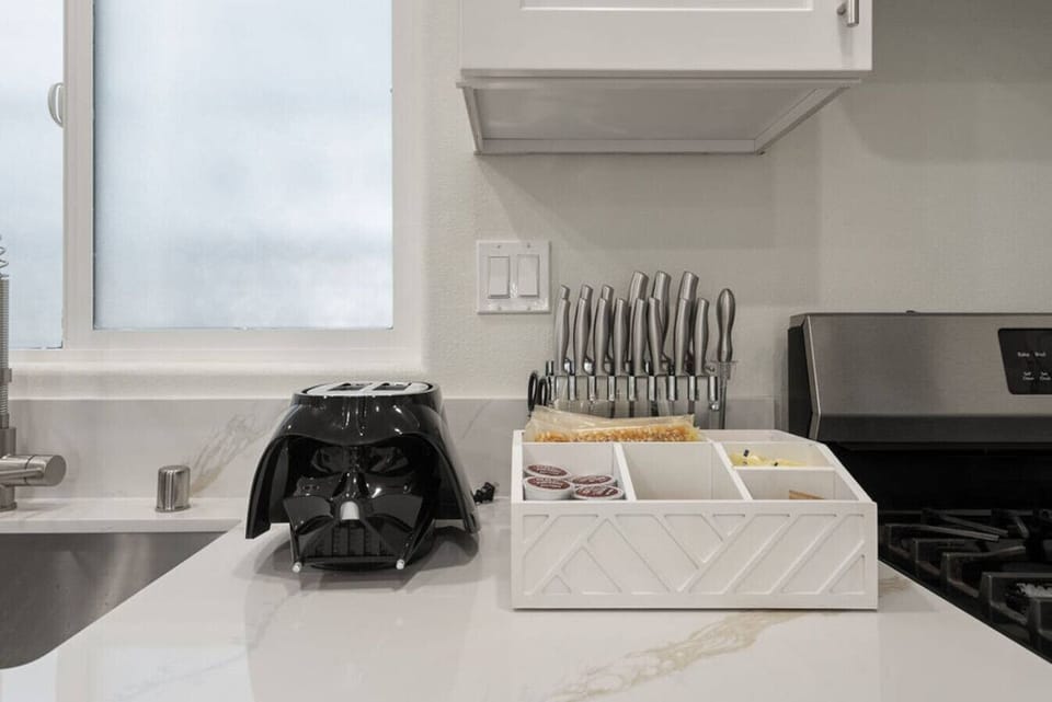Fun, modern kitchen corner 🍽️ featuring sleek countertops, premium knife set 🔪, coffee station ☕, and a bold Darth Vader toaster for a playful sci-fi twist 🚀✨