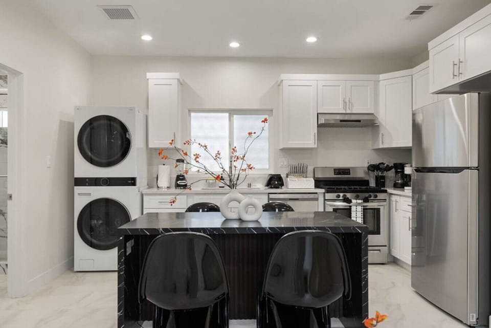 Sleek, fully equipped kitchen ✨ with stainless steel appliances, in-unit washer & dryer 🧺, and a chic black island perfect for dining or gathering 🖤🍽️