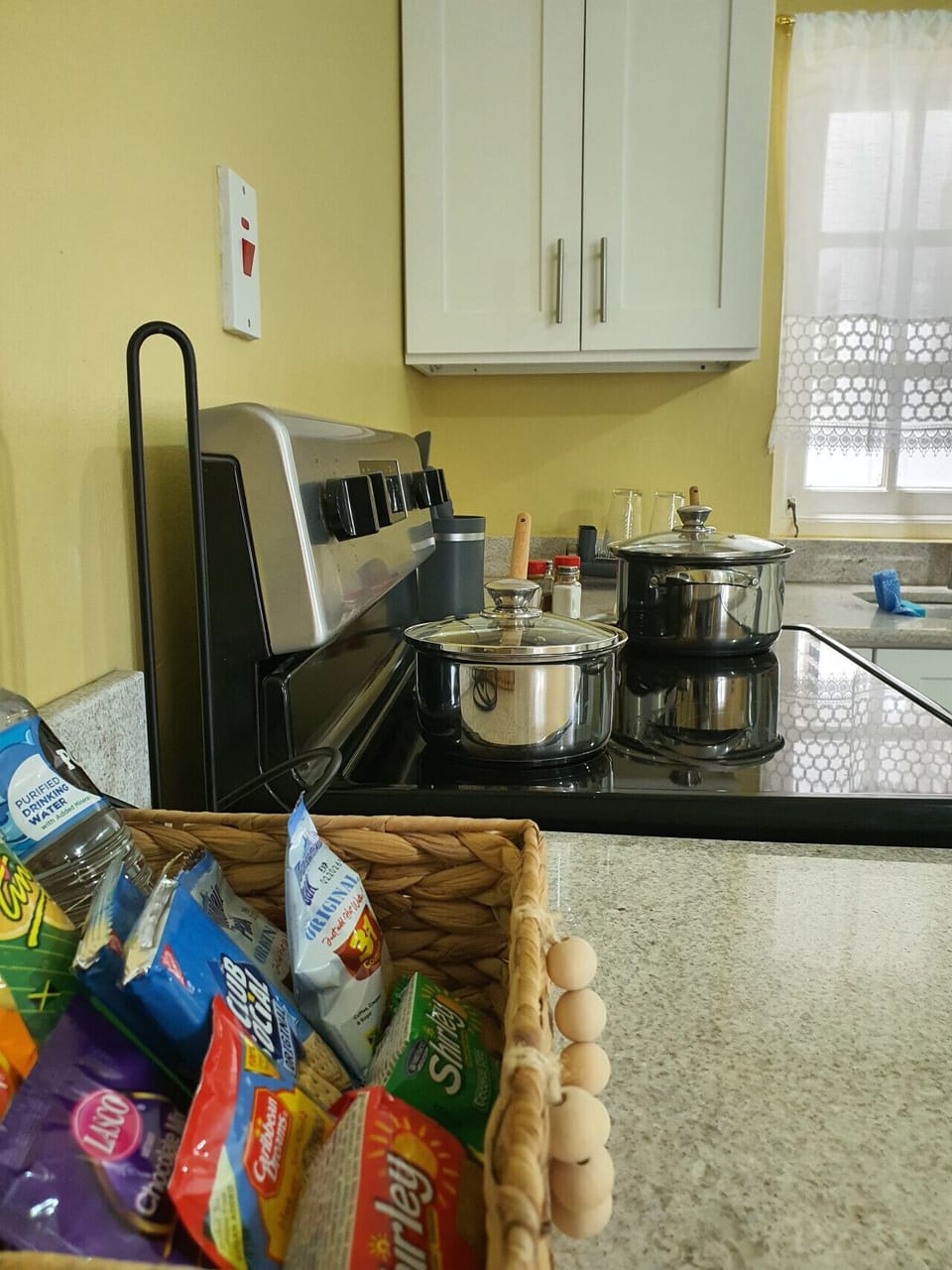 Kitchen counter w/ stovetop & cookware ready for preparing meals at home.