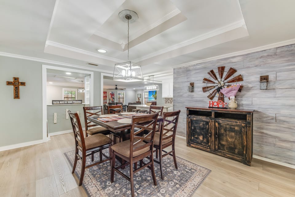 Spacious dining area with seating for six, perfect for family dinners or group meals. Features a modern rustic design and connects to the living room and kitchen, creating an open-concept feel for your Corpus Christi getaway.