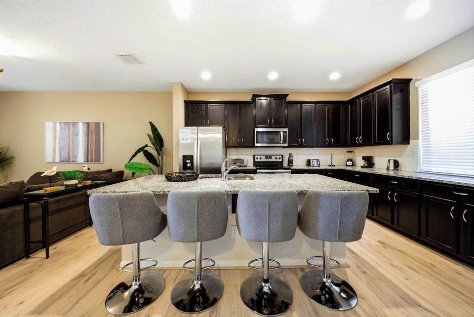 Enjoy a modern kitchen featuring elegant dark cabinetry that contrasts with light hardwood floors. The spacious island with stylish bar stools is ideal for gatherings, and stainless steel appliances add a touch of sophistication.