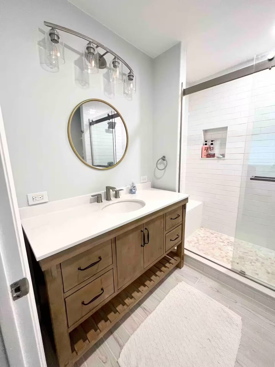 Bathroom with a walk-in tiled shower and round gold mirror
