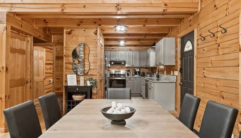 The open-concept layout flows seamlessly into a fully remodeled kitchen, boasting sleek gray cabinetry, stainless steel appliances, and granite countertops. Cedar walls, exposed beams, and loft to second level is visible.
