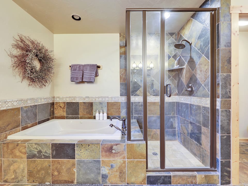 Glass shower enclosure detail in the master bath at Aspen Lodge, Brian Head, Utah. Beautifully tiled and stocked with shampoo, conditioner, and body wash — resort-quality bathroom in a luxury mountain cabin.