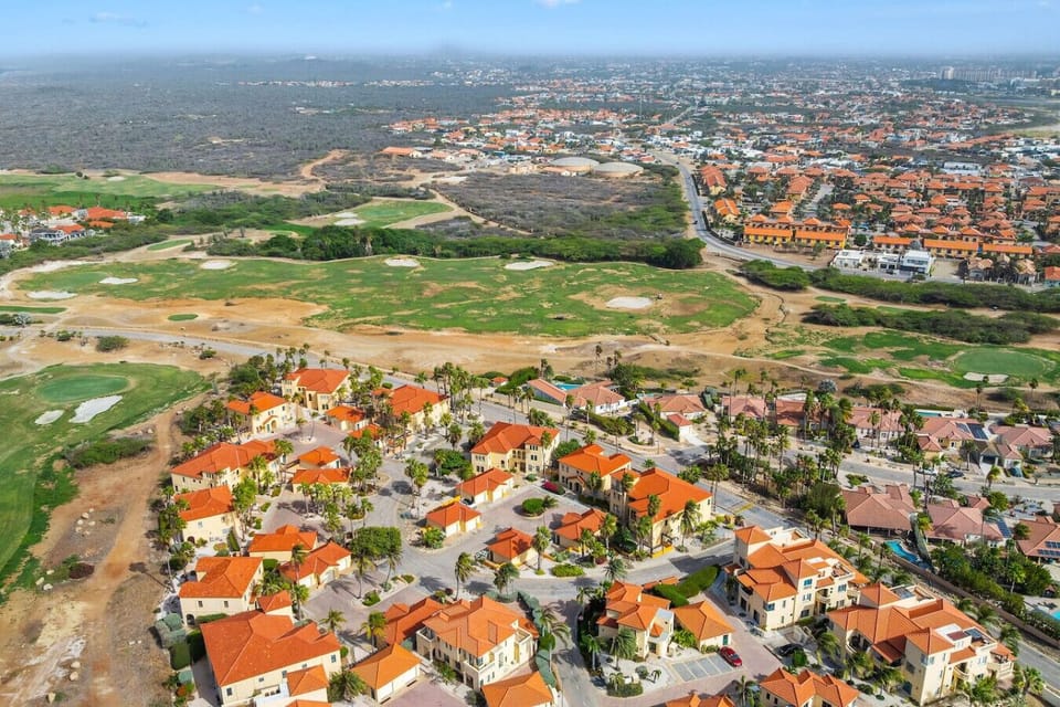 This aerial image showcases a well-planned, Mediterranean-style community with warm-toned stucco homes topped with terracotta roofs.