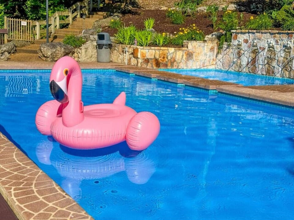 Relax by the sparkling pool at Treetop Village, complete with fun floats and a picturesque waterfall feature, creating a resort like atmosphere.