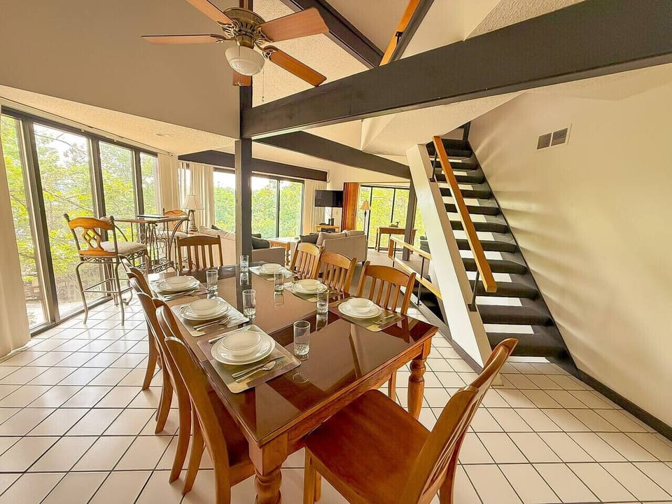 An eight-seater dining area and a bar table with chairs in the corner, offering stunning nature views, this space combines comfort, style, and convenience for a perfect gathering spot.