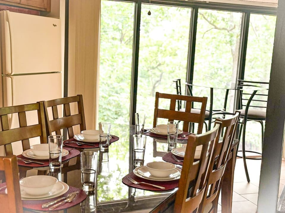 Kitchen and dining with large windows invite nature to peek through, filling the space with natural light and serene outdoor scenery, creating a refreshing and inviting atmosphere.